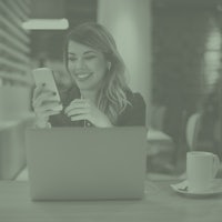 a woman sitting at a table with a laptop and a cup of coffee